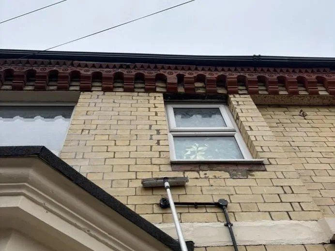 A colourless breathable water repellent being applied to a yellow brick elevation with a long-reach lance