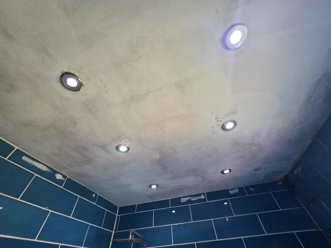 Mould staining across a bathroom ceiling above tiled walls and downlights.
